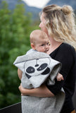 Ein in die Pandabärdecke geschmiegtes Baby auf dem Arm der Mutter