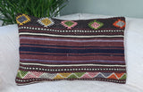 Kilimkissen in brauntoenen mit bunten Ornamenten auf weissem Sofa mit Palme