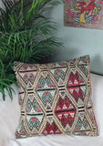 weiss besticktes Dekokissen mit roten ornamenten auf weissem Sofa