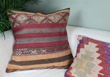 Kelimkissen mit roten Streifen und kleinem Kissen dekoriert auf Sofa