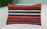 in orange-rot-toenen gestreiftes anatolisches Kilimkissen auf weissem Sofa