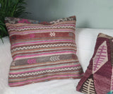 zwei kelimkissen in lila-ros-Toenen auf weissem Sofa
