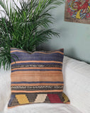 Kelimkissen mit blau-gelben Streifen auf weissem Sofa mit Palme