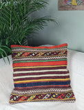 Orientalisches Kilimkissen mit bunten streifen und ornamenten auf weissem sofa mit palme