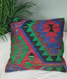 Gemustertes Kelimkissen in kraeftig gruen-rot-blauen Farben auf Sofa