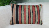 Vintagekissen in gruen-rot-schwarzen Streifen auf weissem Sofa