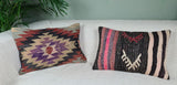 Zwei Vintagekissen mit Mustern und Streifen auf weissem Sofa