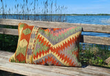 Vintagekissen mit gruen-orangetoenen auf bank am see